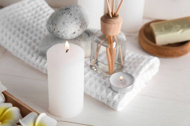 Işık arka planında mum ve spa malzemeleri yakmak