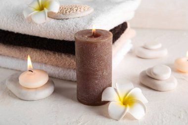 Işık arka planında yanan mumlar, çiçekler ve spa taşları
