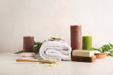 Işık arka planında mum ve spa malzemeleri yakmak