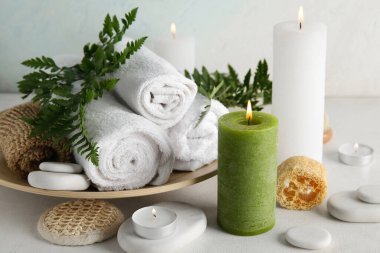 Işık arka planında yanan mumlar, havlular, lifler ve spa taşları