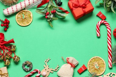 Güzel Noel süslerinden yapılmış çerçeve, ökseotu dalları ve yeşil arka planda hediye kutusu.