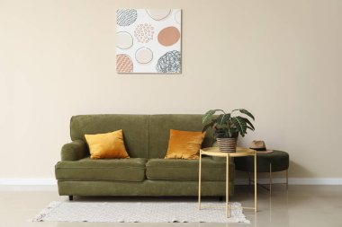 Yeşil kanepe, çiçekli kahve masası ve oturma odasının içi puf.