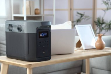 Oturma odasında dizüstü bilgisayarı olan taşınabilir elektrik santrali, yakın plan.