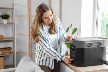 Evde tuvalette taşınabilir elektrik santrali olan genç bir kadın.