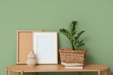 Çerçeveler, vazo ve saksı, yeşil duvarın yanındaki raf ünitesinde. Yakın çekim.