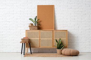 Çekmeceler, ev bitkileri ve beyaz tuğla duvarın yanındaki çerçeve.