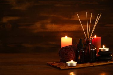 Sazlık dağıtıcı ile spa kompozisyonu ve koyu ahşap masa üzerinde mum yakma