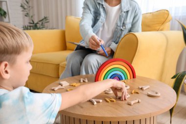 Küçük çocuk konuşma terapistiyle masadan mektuplar alıyor, yakın çekim.