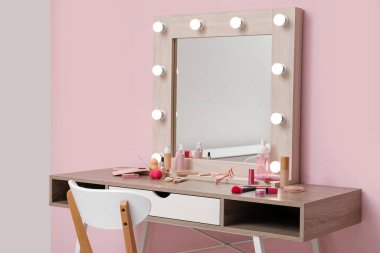 Dekoratif makyaj malzemeleri ve makyaj aksesuarlarıyla birlikte pembe duvarın yanında.