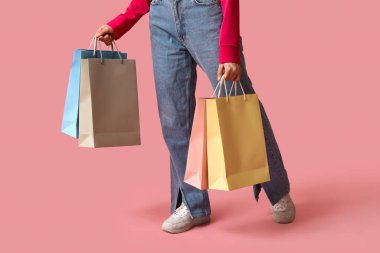 Pembe arka planda alışveriş torbaları olan genç bir kadın. Kara Cuma İndirimi
