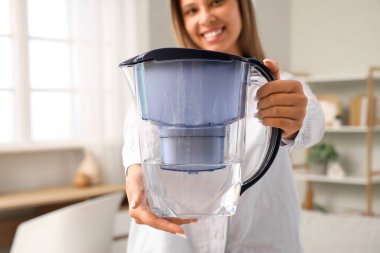 Su filtresi sürahisi olan genç bir kadın.