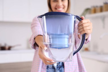 Mutfakta su filtresi sürahisi olan genç bir kadın.