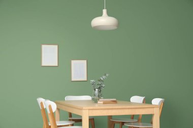 Vazoda okaliptüs dalları ve yemek odasının içindeki kitaplarla dolu bir masa.