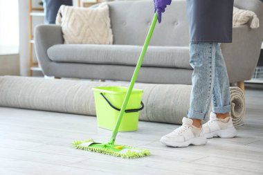 Kadın hademe odayı paspaslıyor.