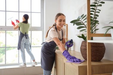 Kadın temizlikçi odada tuvalet temizliyor.