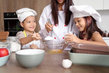 Küçük çocuklarıyla birlikte mutfakta para kazanan Asyalı kadın şef.