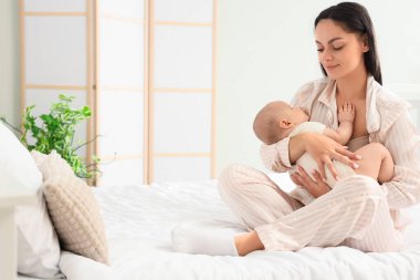 Anne yatak odasında uyumak için bebeğini sallıyor.