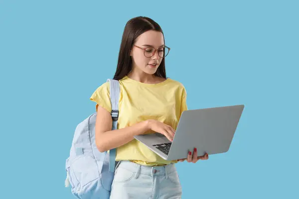 Female student using laptop on blue background