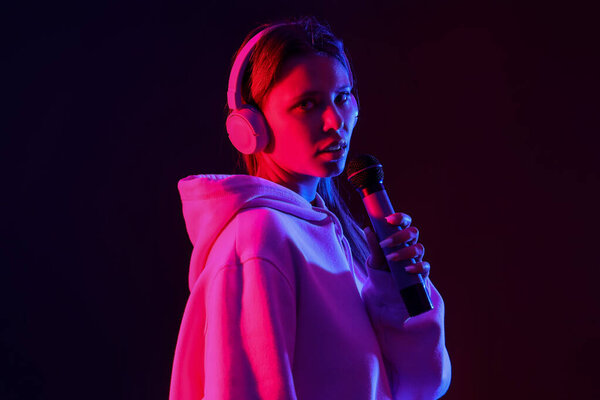 Крутая певица с микрофоном и наушниками на тёмном фоне