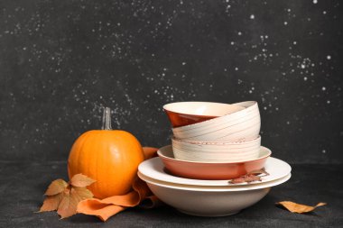 Masada sonbahar dekorlu ve balkabaklı tabak yığını var.