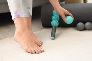 Düz taban, masaj aletleri ve yoga minderi olan genç, sportif bir kadın.