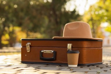 Sonbahar parkında asfalt yolda bir fincan kahve ve şapkayla çanta, yakın plan.