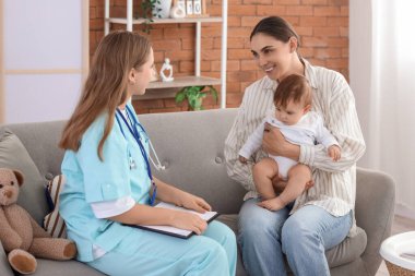 Evde küçük bir bebek ve anneyle çalışan kadın bir çocuk doktoru.