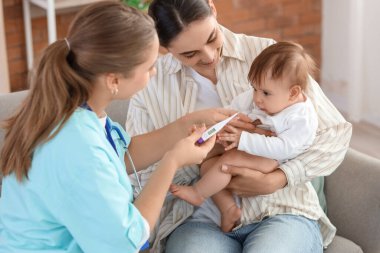 Kadın çocuk doktoru, evde anne ve bebeğin vücut ısısını ölçüyor.