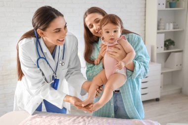 Klinikte küçük bebeği ve annesi olan kadın bir çocuk doktoru.