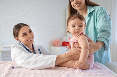 Kanepede bebeği olan kadın bir çocuk doktoru ve klinikte annesi var.