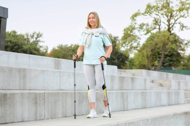 Sportif kadın dışarıda İskandinav yürüyüşü yapıyor.