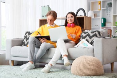 Ofisteki kanepede dizüstü bilgisayar ve tabletle çalışan birkaç grafik tasarımcısı.