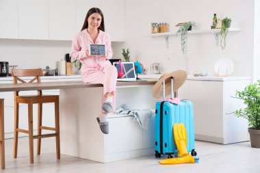 Tablet bilgisayarlı kadın turist mutfaktaki otel odasını ayarlıyor.