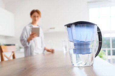 Mutfakta tablet bilgisayarı olan adama karşı su filtresi testi, yakın plan.