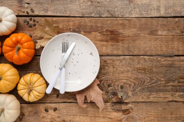 Ahşap arka planda taze balkabakları, tohumları ve sonbahar yapraklarıyla güzel bir masa.