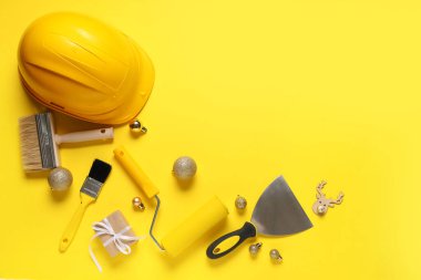 Hediyeli inşaat aletleri ve sarı arka planda Noel topları.
