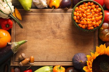 Arka planda farklı taze sebzeler, meyveler ve ayçiçekli ahşap tahta var. Hasat festivali