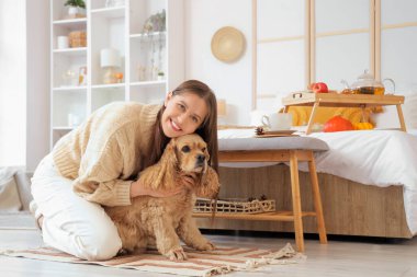 Güzel, genç, mutlu bir kadın ve evde bir fincan yeşil çayla sevimli Cocker Spaniel köpeği.