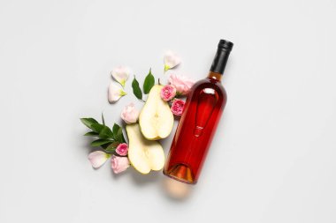 Gül çiçekli bir şişe şarap, armut yarımları ve beyaz arka planda yapraklar