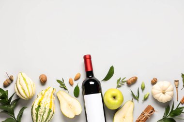 Beyaz arka planda meyve, balkabağı ve yapraklı bir şişe şarap.