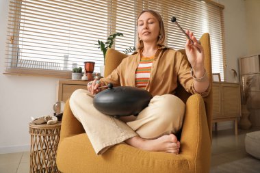 Evdeki koltukta glukofon çalan güzel bir kadın.