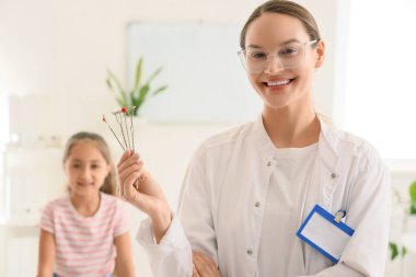 Ofisteki küçük kıza karşı logopedik araştırma yapan kadın konuşma terapisti.