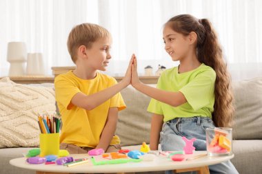 Küçük çocuklar evde birbirlerine beşlik çakıyorlar.