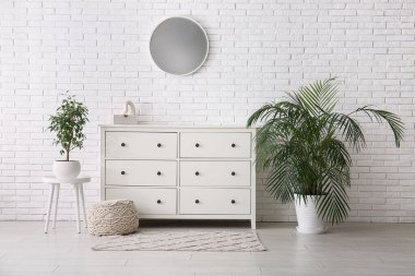 Çekmeceleri, çiçekleri ve aynaları olan güzel bir oda.