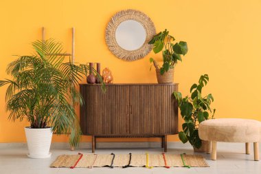 Çekmeceler, puf, ev bitkileri ve aynalar oturma odasının içinde.