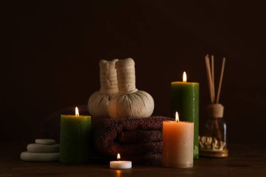 Kaplıca aksesuarları ve koyu renk arka plana karşı ahşap masada mum yakma kompozisyonu