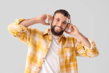 Gri arka planda kulaklıklı yakışıklı genç adam.