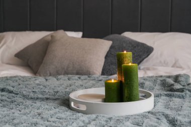 Yatak odasında üzerinde yeşil mumlar olan tepsi. Yakın çekim.