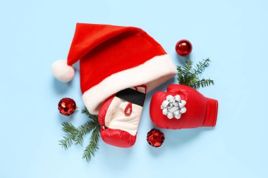 Boks eldivenli kompozisyon, Noel Baba şapkası ve arka planda Noel süslemeleri.