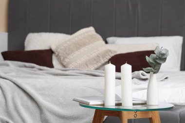 Mumlar, açık kitap ve yatağın yanında okaliptüs dalı.